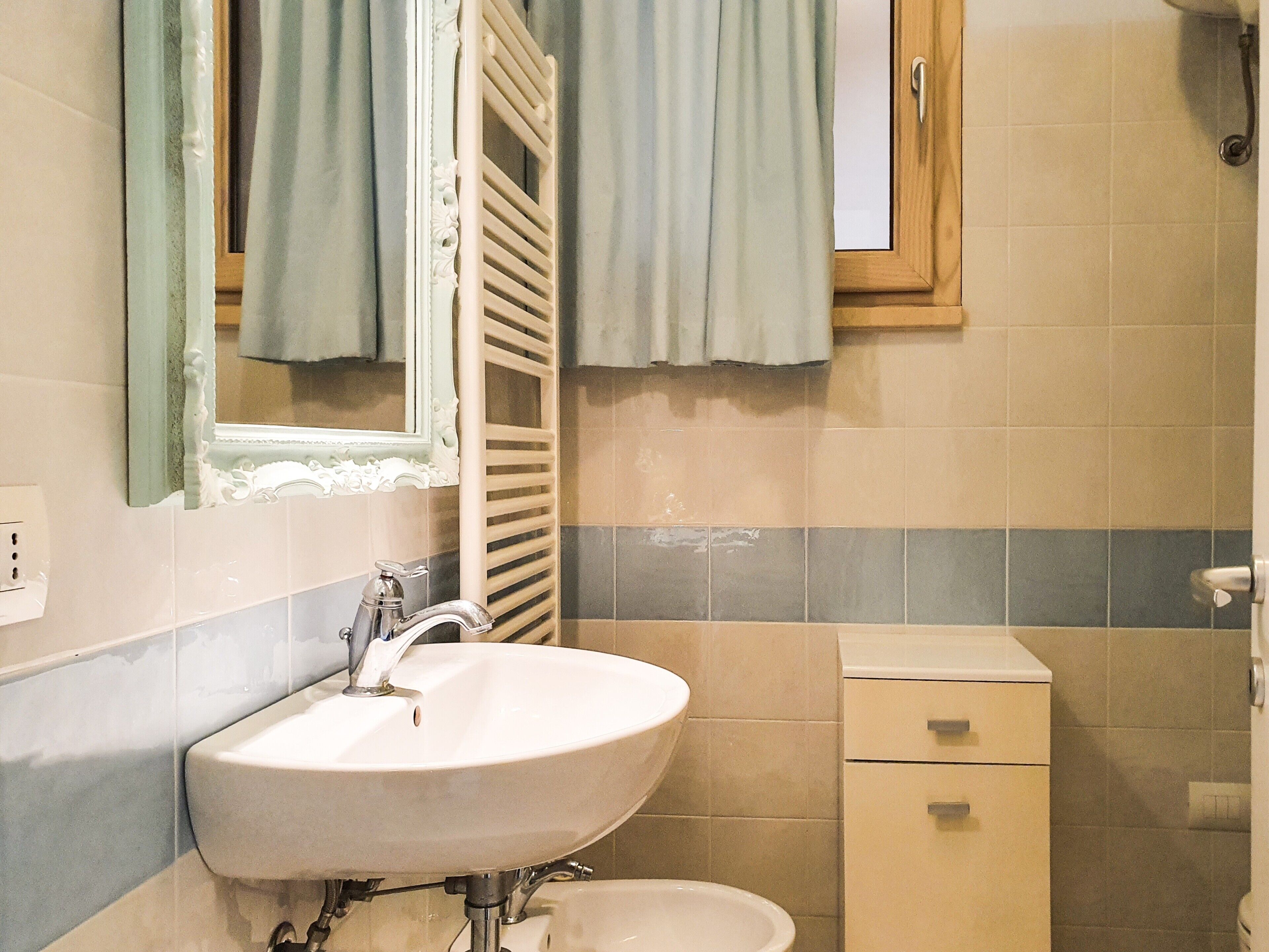 A bathroom with a sink, mirror, towel rack, and a small cabinet.