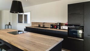 A modern kitchen with a wooden countertop, black cabinets, a built-in oven, and a pendant light. - Private pool villa - 5* (Plurien)