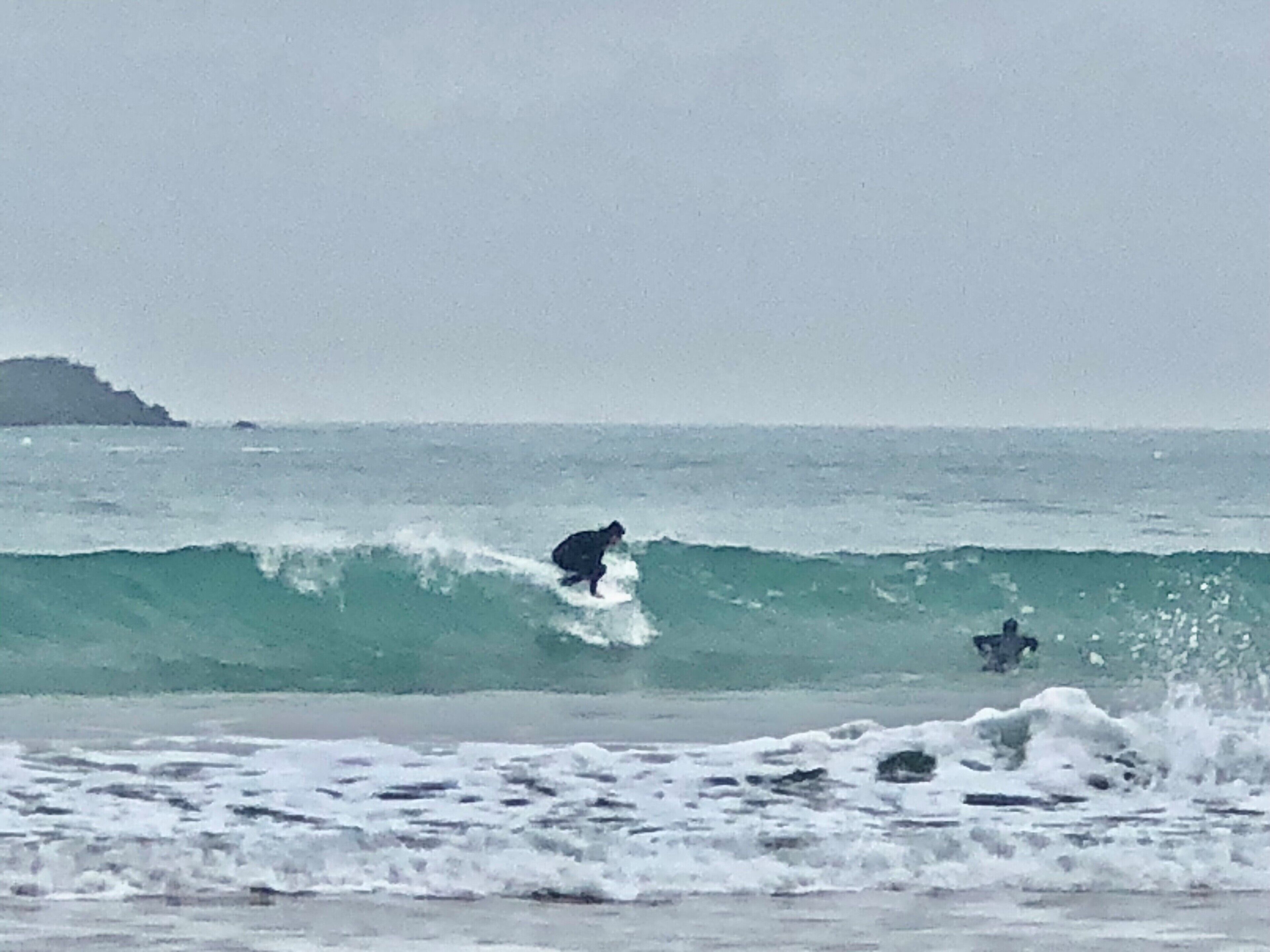 Escena de playa con olas y una masa de tierra en la distancia.