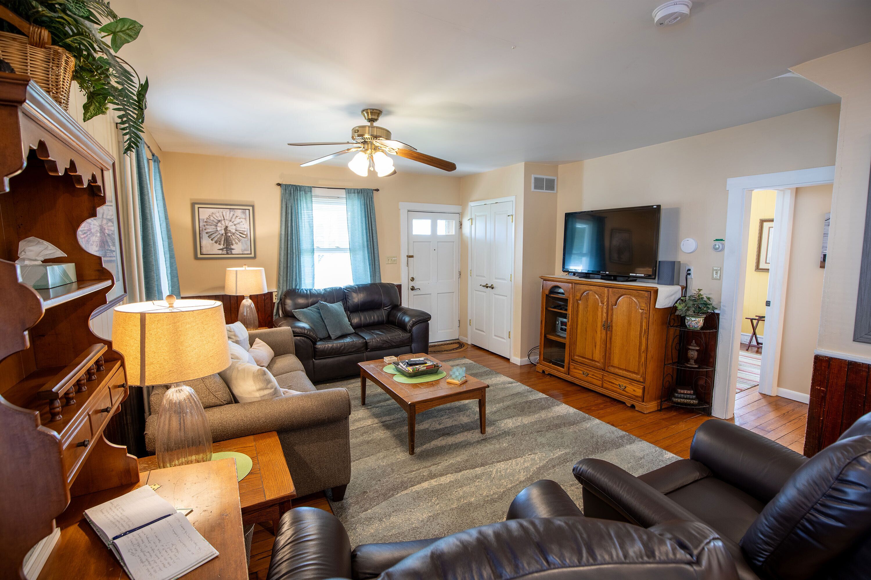 A living room with a sofa, a coffee table, a television, and a ceiling fan.