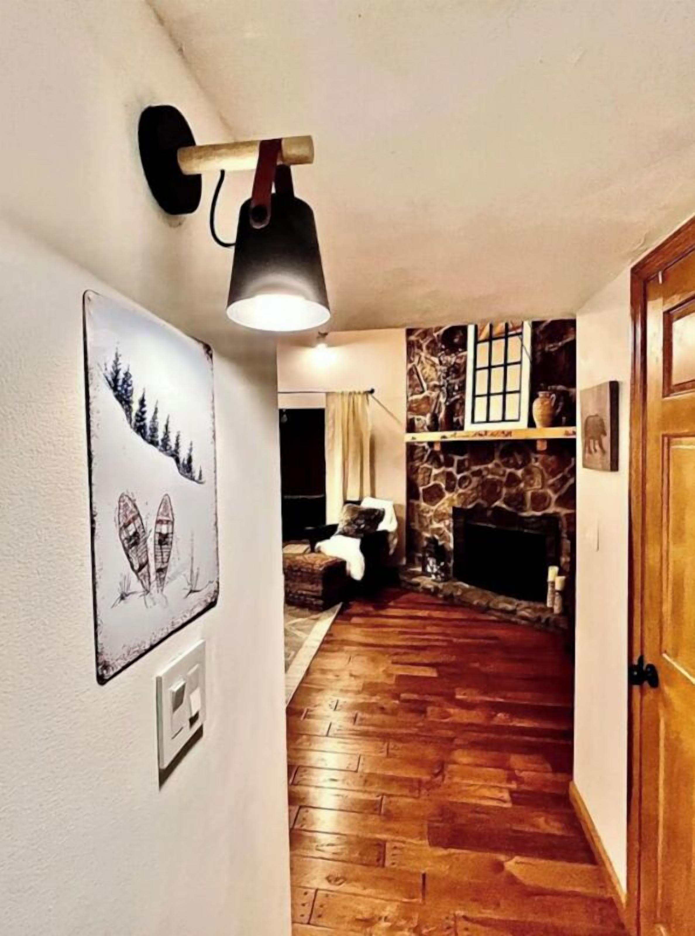 Un soggiorno con camino in pietra, pavimento in legno e un'opera d'arte appesa al muro.