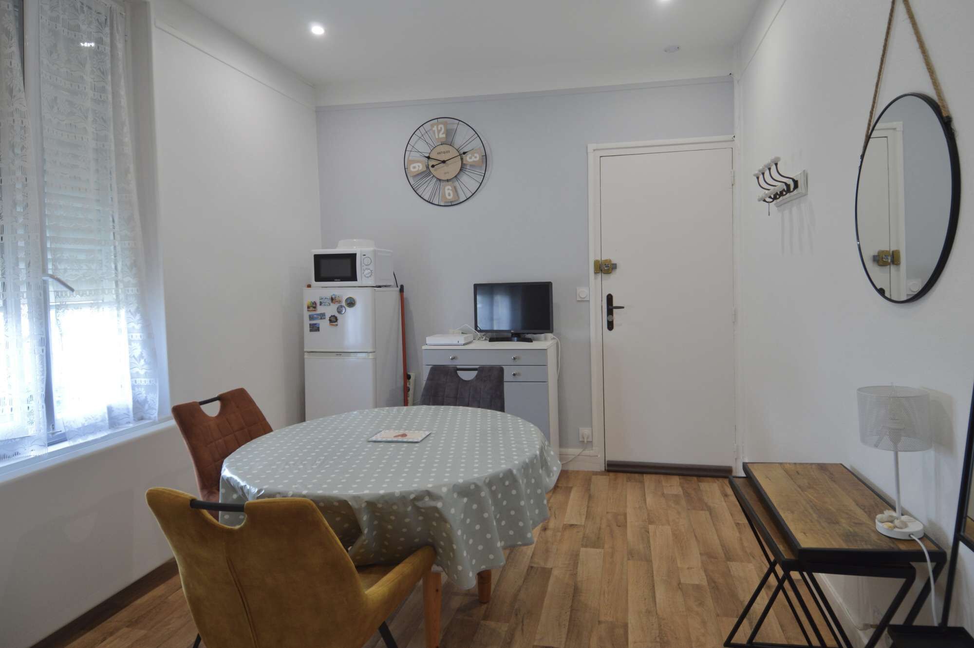 Un espace de vie compact comprenant une table à manger, des chaises, un four à micro-ondes, un téléviseur et une horloge murale.