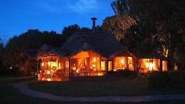 A thatched-roof building with multiple rooms, a central fireplace, and a paved pathway leading to it. - Chui Lodge (Naivasha)