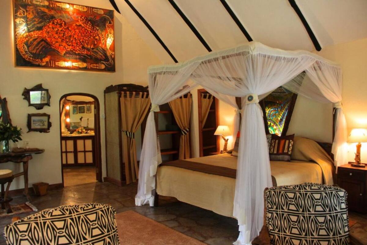 Quarto com cama de dossel, um quadro grande na parede e uma janela de vitrais.