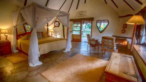 A bedroom with a four-poster bed, a wooden chest, and a chair. - Chui Lodge (Naivasha)