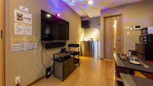 Una habitación de hotel moderna con televisión de pantalla plana, una kitchenette pequeña y un comedor.