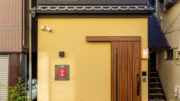 Un edificio con fachada amarilla, puerta de madera y un letrero con caracteres japoneses.
