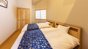 Un dormitorio con dos camas, una ventana con rejas, un armario de madera y un equipo de aire acondicionado.