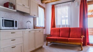 A kitchen with a microwave, cabinets, and a red sofa. - Apartment "Sunflower", Agriturismo dai Gobbi (Fara Vicentino)