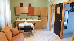 Un espacio habitable compacto con kitchenette, comedor y un pequeño sofá.