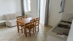 Ett kompakt kök med ett matbord, stolar, en soffa och en diskho.
