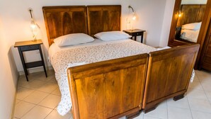 Un lit en bois avec une tête de lit, deux tables de chevet et un miroir au mur.