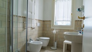 Une salle de bain avec une douche à parois de verre, un bidet, des toilettes et un lavabo.