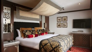 Une chambre d’hôtel avec un grand lit, une télévision, une armoire et une tête de lit décorative.