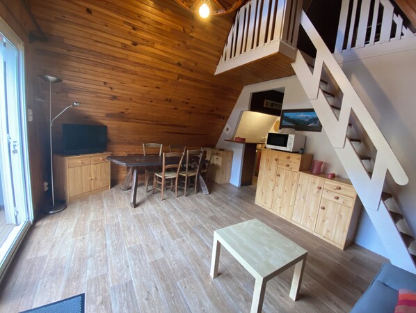 A cozy wooden interior with a dining area, a small table, and a staircase.