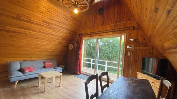 Una cabaña acogedora de madera con sofá, mesa y sillas.