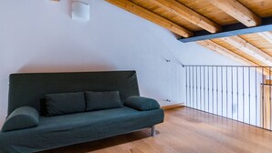 Une chambre moderne avec un plafond en bois, un canapé vert et une vue sur l’extérieur depuis un balcon.