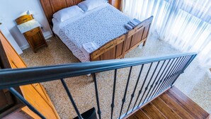 Une chambre à coucher avec un lit en bois, une table de chevet et une fenêtre ornée de rideaux légers.