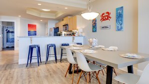 Una cocina moderna con una isla central, taburetes de bar y una mesa de comedor para cuatro.