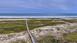 Un paisaje costero con un paseo de madera que conduce a una playa.