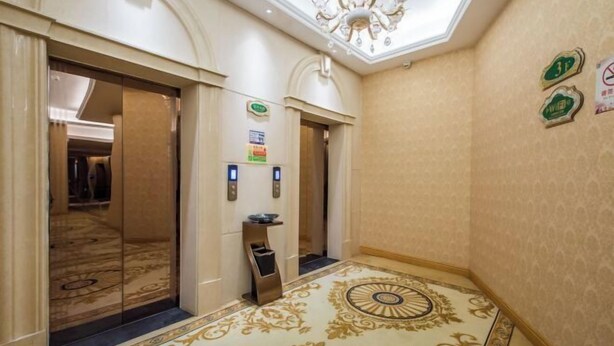 A hallway with two elevators, a patterned carpet, and a chandelier. - Vienna Hotel (Kunshan Convention and Exhibition Center) (Kunshan)