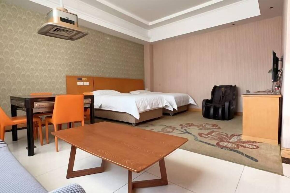 A hotel room with a bed, a desk, two chairs, a table, and a television.