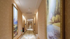 A hallway with patterned carpet, framed artwork on the walls, and a large painting of swans. - Vienna Hotel (Kunshan Convention and Exhibition Center) (Kunshan)