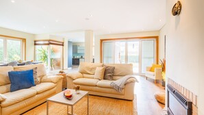 A modern living room with a beige sofa, a coffee table, and a fireplace. - Furadouro Sunny Family Villa (Ovar)