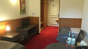 Habitación de hotel con cama, escritorio con computadora, televisor, alfombra roja y un cuadro en la pared.
