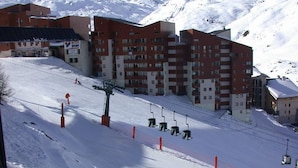 Een skigebied met een stoeltjeslift, gebouwen en een besneeuwde berg op de achtergrond.