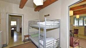 A bunk bed room with a wooden ceiling, a small table, and a chair. - Chalet Vignarola (Orbetello)