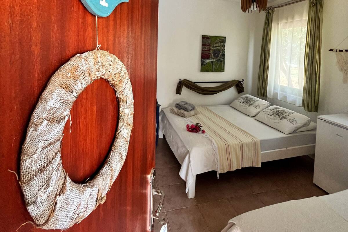 A bedroom with a bed, a small desk, a wall-mounted sign, and a woven basket.