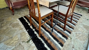 Een eetruimte met een tafel voor vier personen, omringd door houten stoelen met zitkussens.