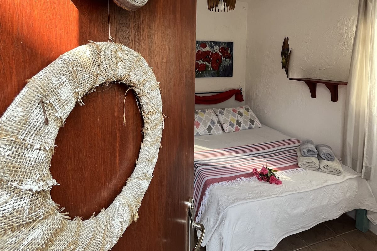 A bedroom with a bed, a wooden door, and a wall-mounted painting.
