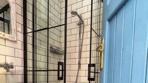 Een badkamer met een witte wastafel, een douche met glazen wanden en vloertegels met een patroon.