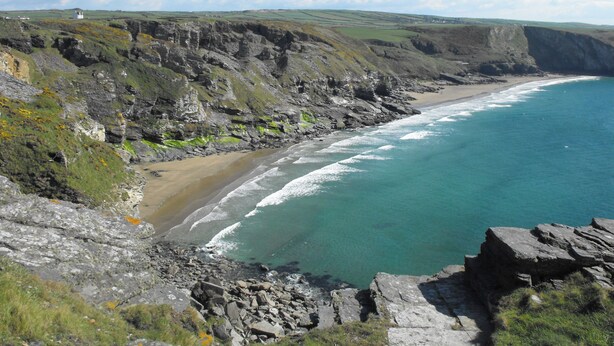 A coastal landscape with rocky cliffs, a beach, and a clear blue sea. - Trelash Cottage (Launceston)