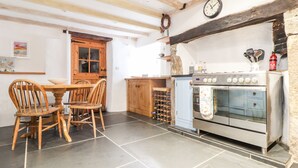 A kitchen with a wooden table and chairs, a wine rack, and a stove. - Trelash Cottage (Launceston)