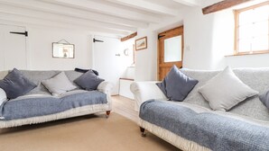 A spacious living room with two sofas, a wooden ceiling, and a large window. - Trelash Cottage (Launceston)