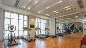 Un gimnasio espacioso con cintas de correr, una bicicleta estática y una máquina de remo.