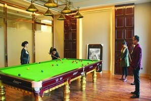 A pool table in a room with wooden flooring and a mirror on one wall. - Jun Jia Hotel (Tianmen)