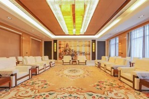 A spacious room with a large, ornate carpet, several sofas arranged in a semi-circle, and a large painting on the back wall. - Jun Jia Hotel (Tianmen)