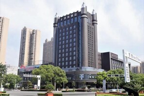 A high-rise building with a modern design, featuring a prominent entrance and surrounding greenery. - Jun Jia Hotel (Tianmen)