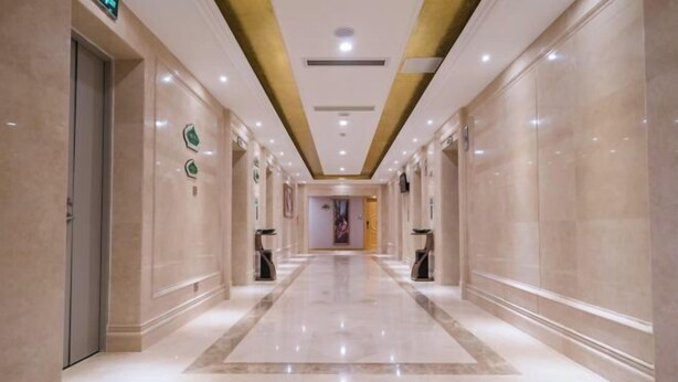 A long, well-lit hallway with marble floors and walls, leading to a door at the end. - Vienna Hotel (Jiangmen Wanda Plaza Store) (Jiangmen)