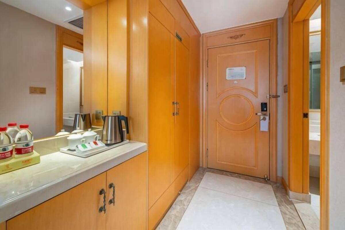A hotel room with wooden cabinets, a sink, and a door with a lock.