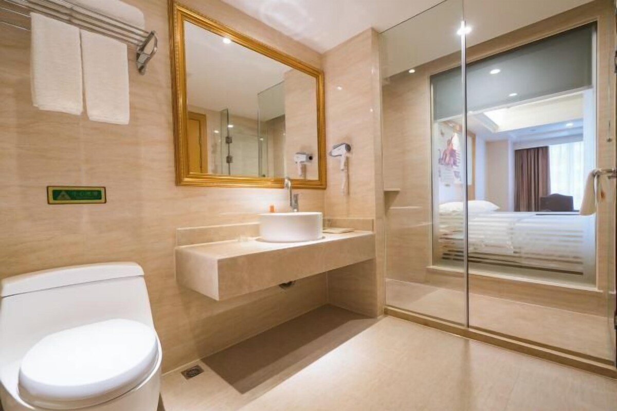 A modern bathroom with a toilet, sink, and a large mirror.