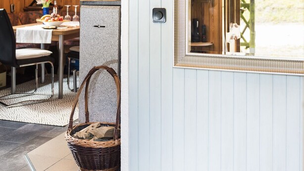 Une pièce chaleureuse avec un plafond en bois, un coin repas comprenant une table et des chaises, un panier en osier et une fenêtre agrémentée d’un miroir décoratif.