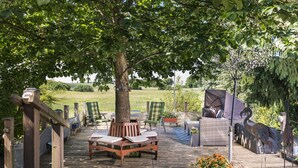 Une terrasse extérieure avec des meubles en bois, un arbre et une statue de flamant décorative.