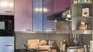 Une cuisine moderne avec des meubles de couleur violette, un évier en acier inoxydable et un four à micro-ondes.