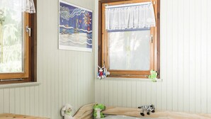 Une pièce confortable avec un lit, une petite table, une chaise et une fenêtre avec des rideaux.