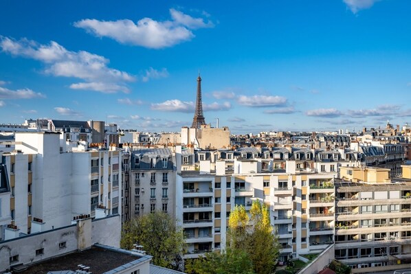 A high-rise building with multiple balconies and a view of the Eiffel Tower in the background. - The Salon in the Sky, by Veeve (Paris)